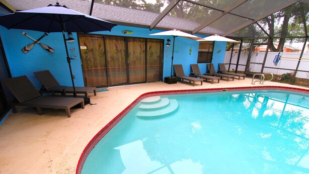Zona de piscina con sillones, sombrillas y una sección cubierta.