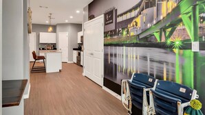 Una habitación de hotel moderna con suelo de madera, una zona de cocina y un mural con un paisaje urbano.