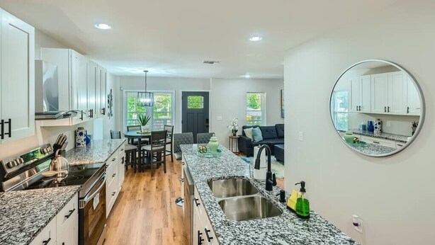 A modern kitchen with granite countertops, stainless steel appliances, and a dining area with a table and chairs. - Elegant Atlanta Haven | 3 Bedroom Near Downtown (Atlanta)
