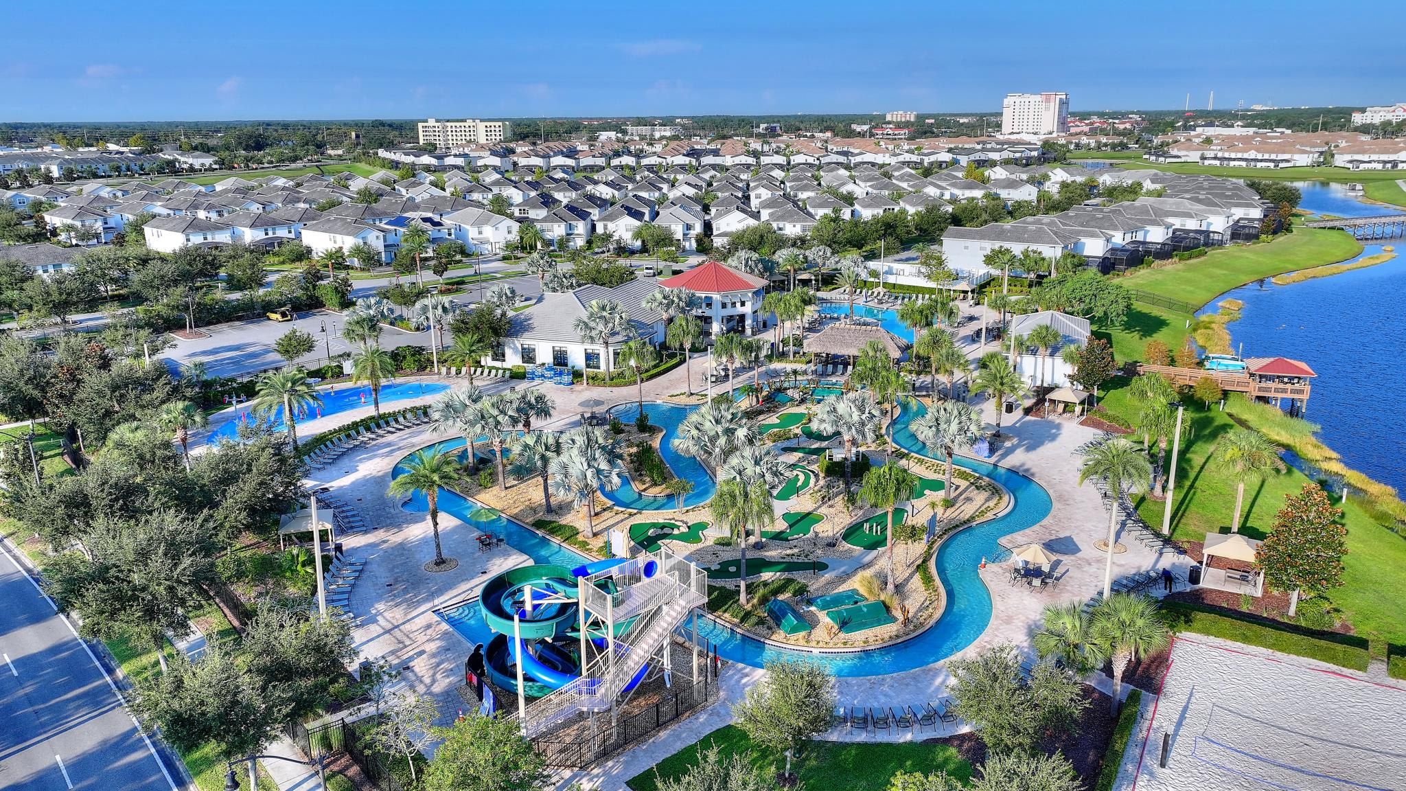 A resort with a large pool area, a water slide, and a view of the surrounding residential area.