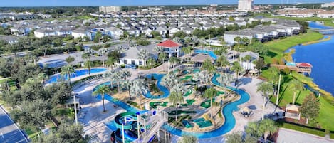 A resort with a large pool area, a water slide, and a view of the surrounding residential area.