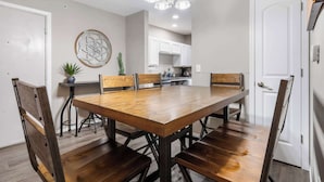 A dining area with a wooden table and chairs, a chandelier, and a kitchen in the background. - The Moab - Swimming Pool! (Branson)