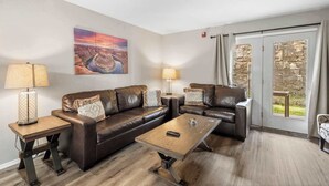 A living room with a sofa set, two side tables with lamps, a coffee table, and a large window with curtains. - The Moab - Swimming Pool! (Branson)