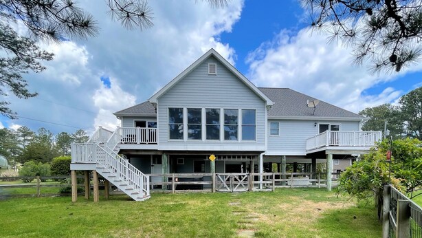 A two-story house with a front porch, a covered deck, and a staircase leading to the upper level.
