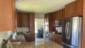 A modern kitchen with granite countertops, stainless steel appliances, and wooden cabinets.