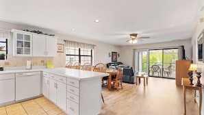 Una cocina amplia con comedor, ventilador de techo y vistas a un balcón.