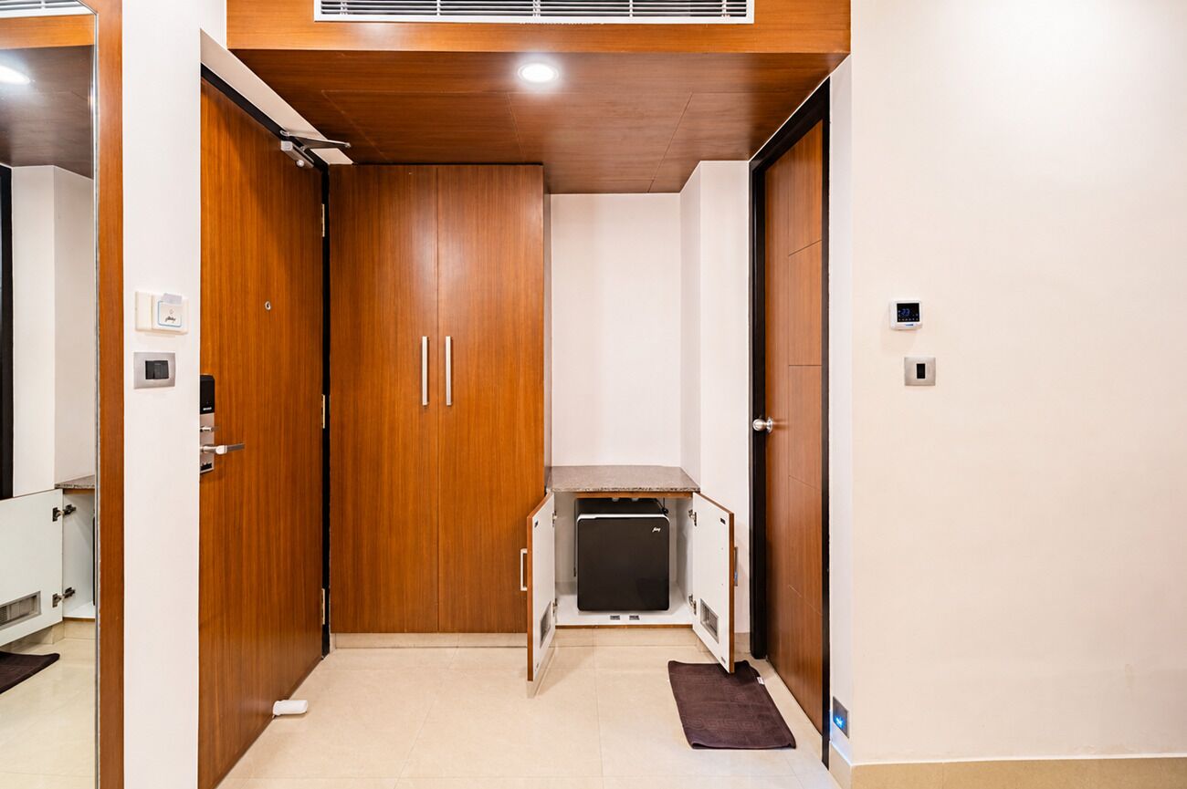 A compact room with a wooden wardrobe, a small kitchenette, and a built-in heater.