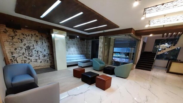 A modern living room with a marble floor, a sofa, a chair, and a coffee table. There is a staircase in the background. - La Grrande Malar - The Boutique Hotel Pondicherry (Puducherry)