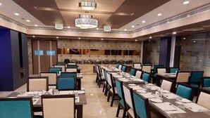 A spacious dining area with multiple tables and chairs, a patterned wall, and a modern chandelier. - La Grrande Malar - The Boutique Hotel Pondicherry (Puducherry)