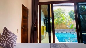 Ein Schlafzimmer mit einer großen Schiebeglastür, die zu einem Poolbereich führt.
