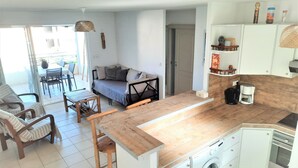 Een knus woongedeelte met een kitchenette, een eethoek en een bank.