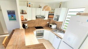 Een keuken met een houten aanrecht, witte kasten, een ingebouwde oven, een magnetron en een koelkast.