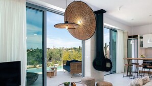A modern living room with a large glass door leading to a balcony, a fireplace, and a kitchen area with bar stools.