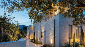 A modern building with a stone facade, a paved pathway, and a well-lit entrance.