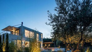 A modern two-story house with large windows, a balcony, and a well-lit garden area. - Heniochos Grande Seaview 3BD 3BA (Daratsos)