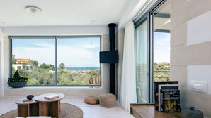 A modern living room with a large window, a flat-screen TV, and a cozy seating area. - Heniochos Grande Seaview 3BD 3BA (Daratsos)