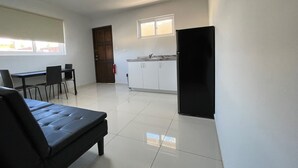 Een moderne keuken met witte kasten, een zwarte koelkast en een eethoek met een bank en stoelen.