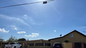 Een gebouw met een hek en een oprit met een witte vrachtwagen en een personenauto.