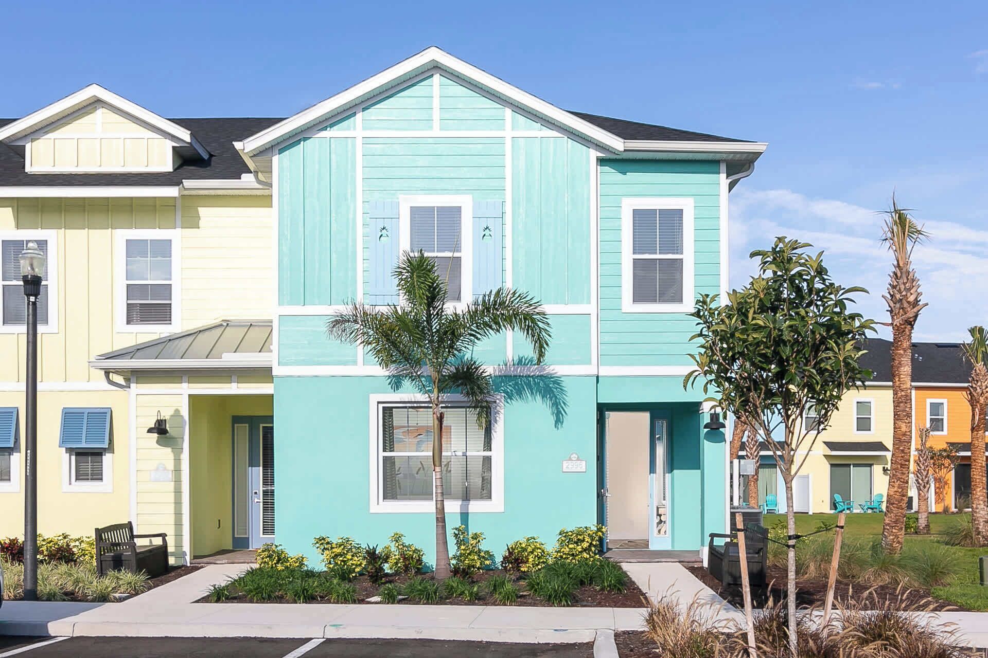 A two-story building with a light blue facade, a flat roof, and a small front porch with a bench.