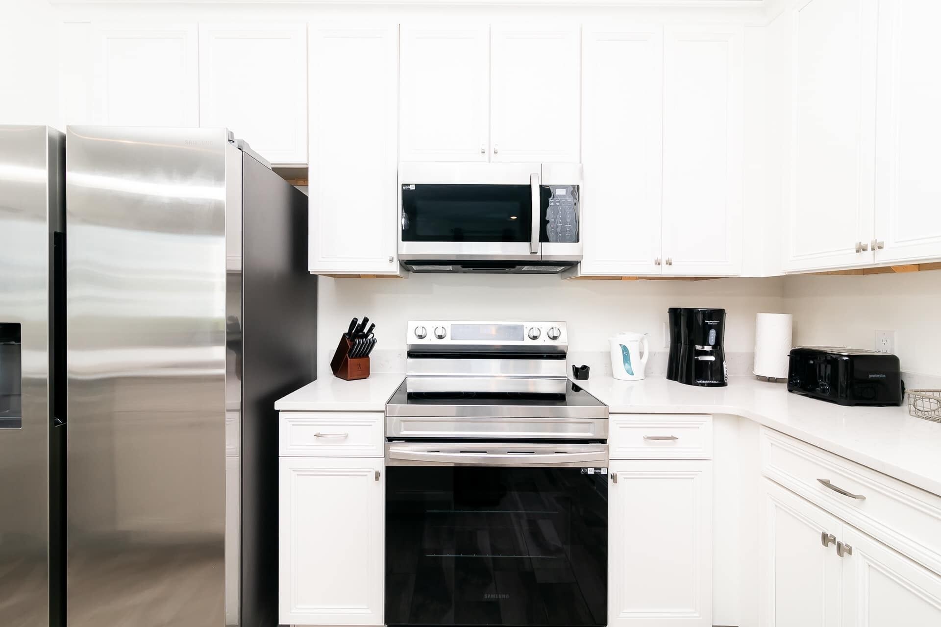 Una cucina moderna con elettrodomestici in acciaio inossidabile, mobili bianchi e forno integrato.