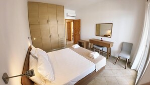 Una camera d'albergo con un letto, una scrivania, una sedia, un armadio e uno specchio.