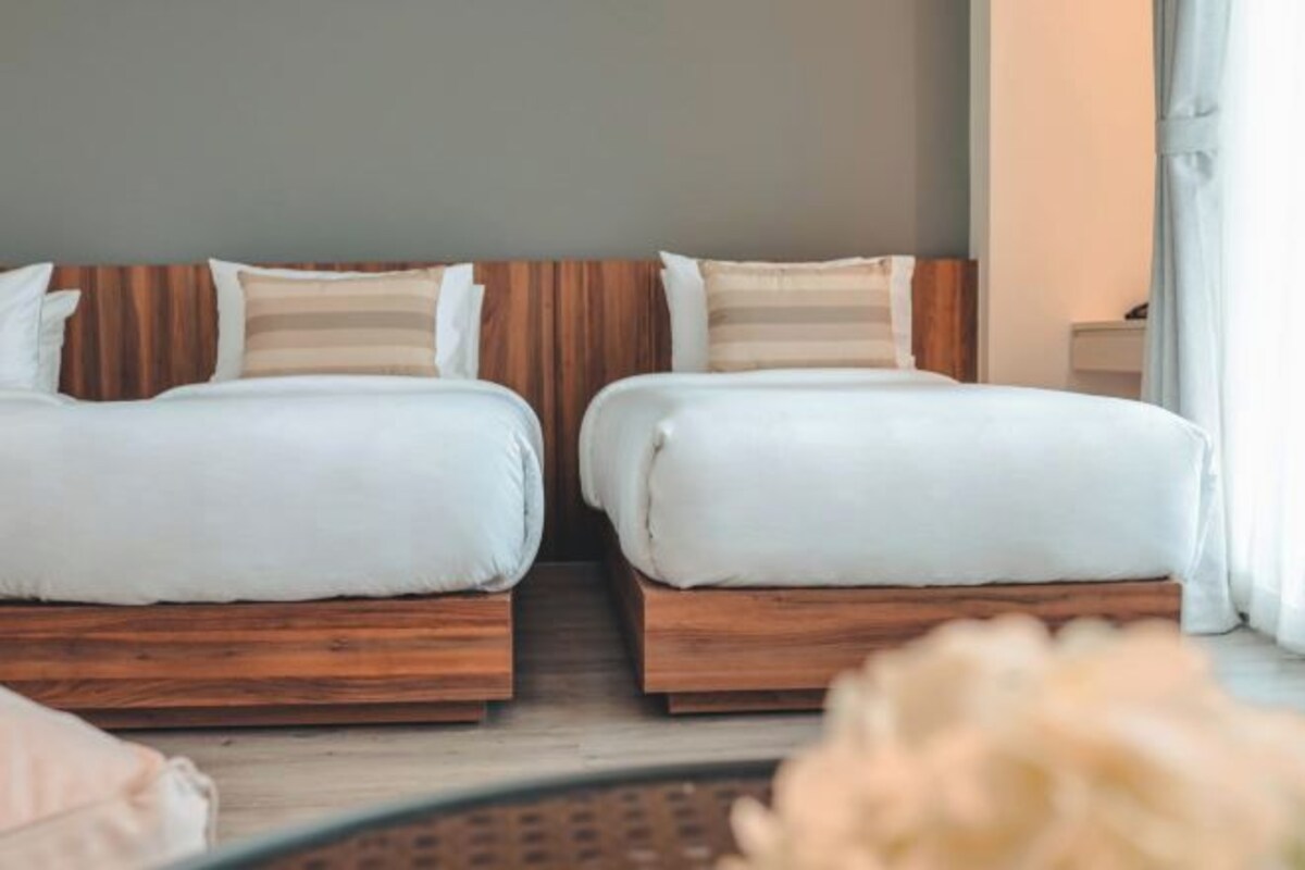 A hotel room with two beds, wooden headboards, and a neutral color scheme.