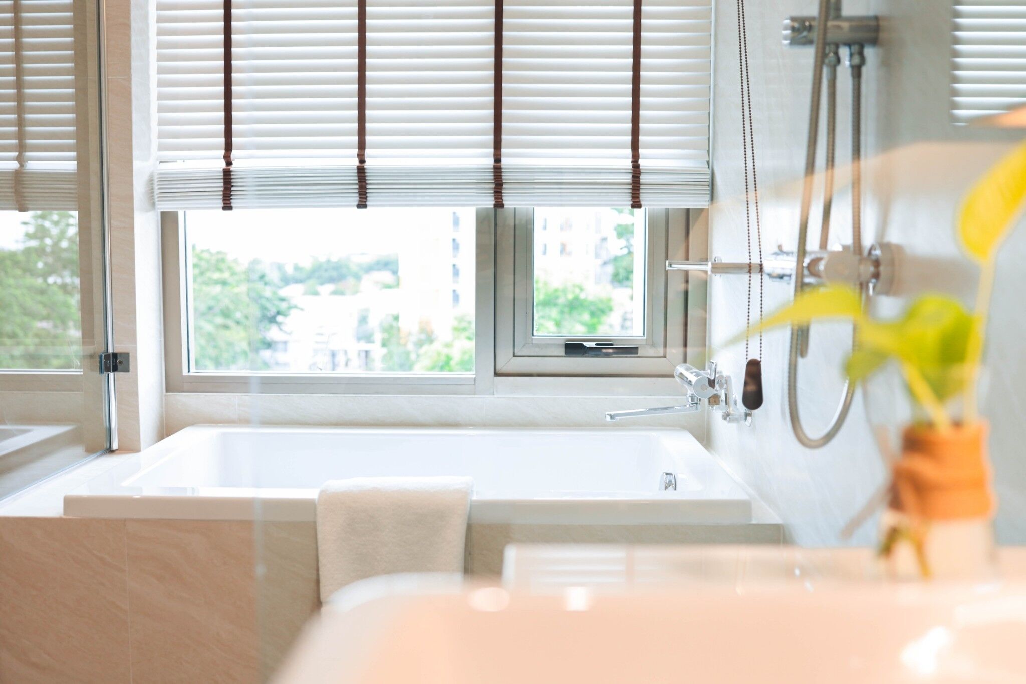 Une salle de bain moderne avec une baignoire, une douche et une fenêtre équipée de stores.