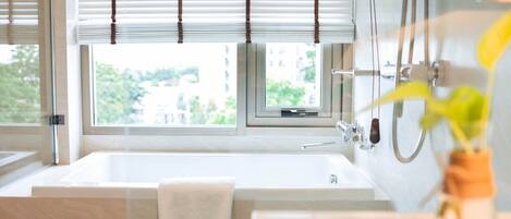 Une salle de bain moderne avec une baignoire, une douche et une fenêtre équipée de stores.