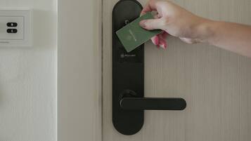 A hand holding a green card near a black card reader on a door.
