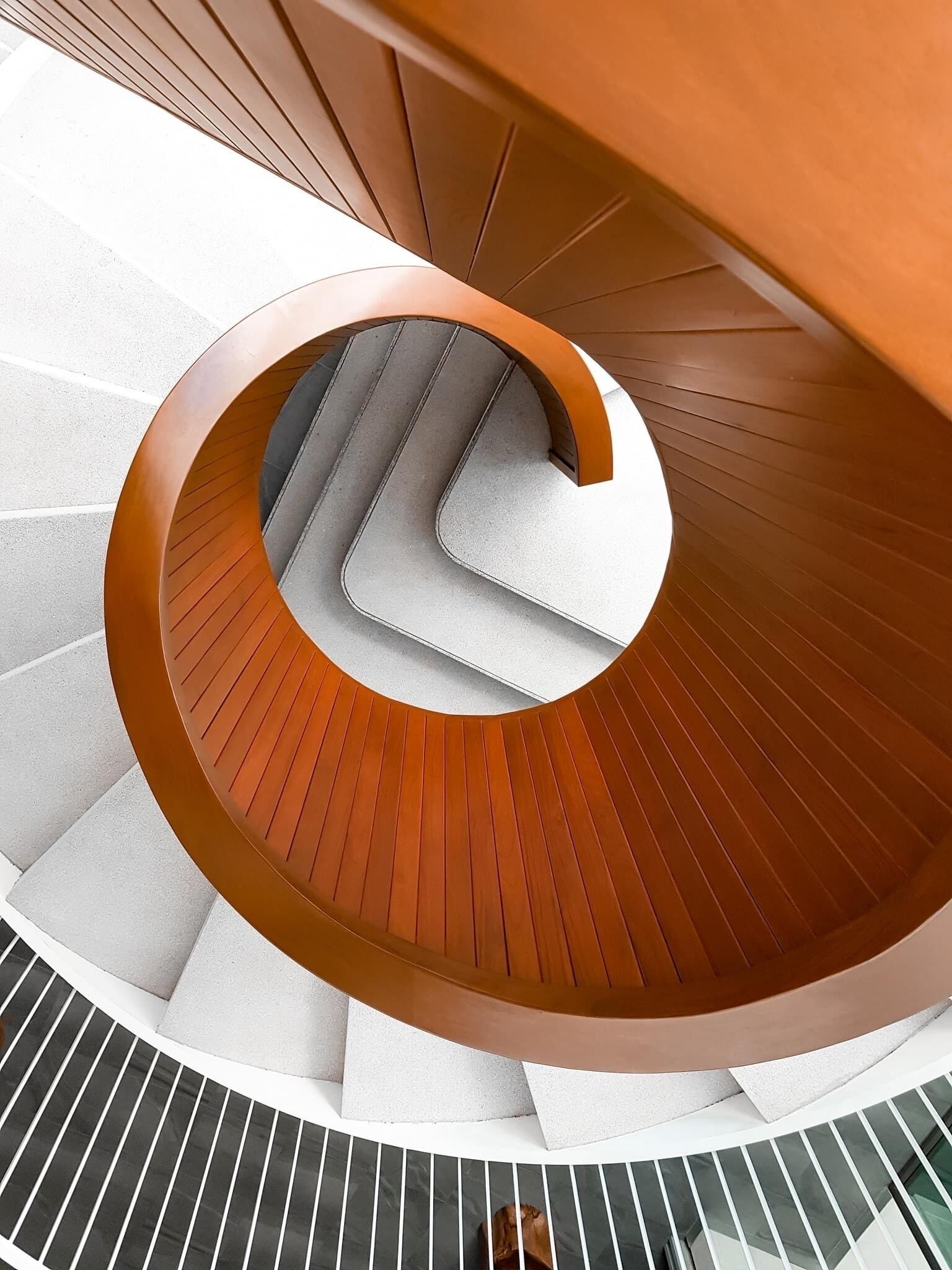 Una escalera de caracol con escalones de madera y barandilla blanca.