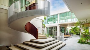 A modern spiral staircase with a wooden handrail and beige steps, leading to a glass-enclosed upper level. - Welladee Wellness Chiang Mai (Chiang Mai)