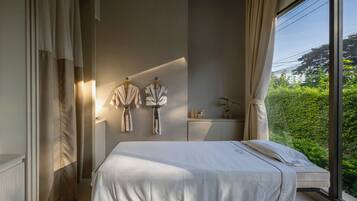 Enjoy a peaceful retreat with a neatly made bed and a serene view of lush greenery.