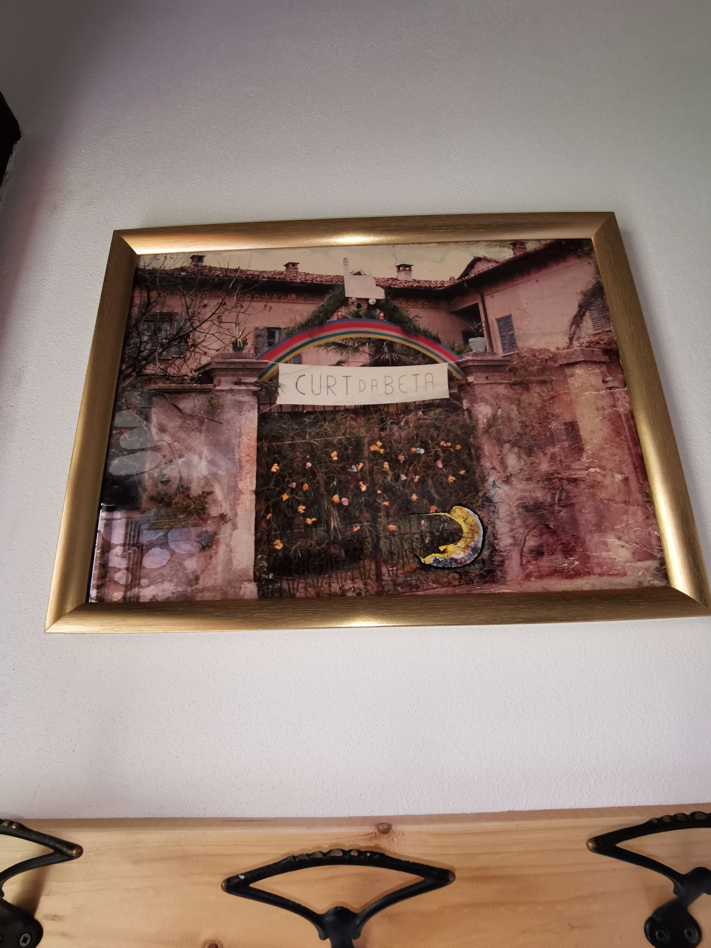 A framed artwork of a building with a sign reading "CURT DABETA" and a rainbow arch.