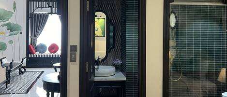 A modern bathroom with a large mirror, a sink, and a shower area.