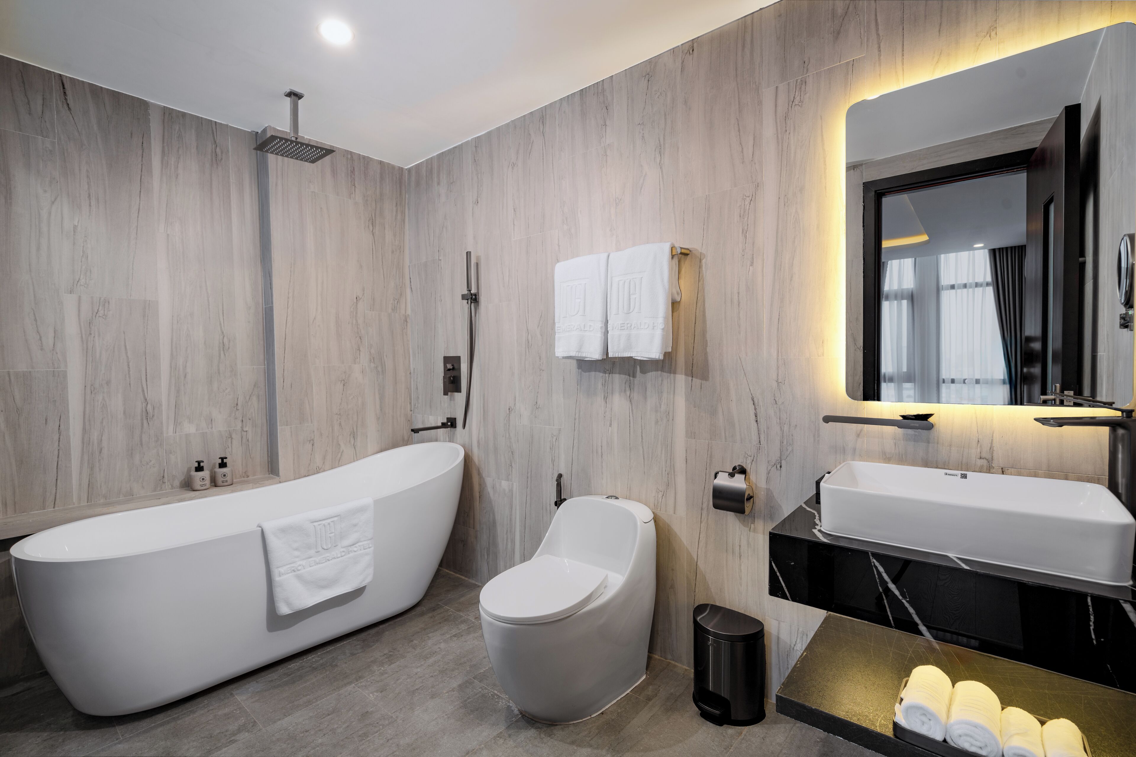 A modern bathroom with a freestanding bathtub, a toilet, a sink, and a mirror.