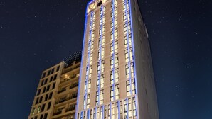 A tall hotel with illuminated blue lines on the facade, named "Mercy Emerald Hotel."