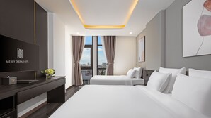 A modern hotel room with a large bed, a TV, and a desk with a flower vase. - MERCY EMERALD HOTEL (Da Nang)
