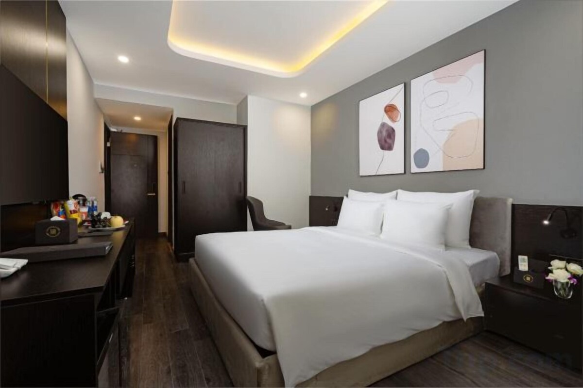 A hotel room with a bed, bedside table, desk, and a wardrobe.