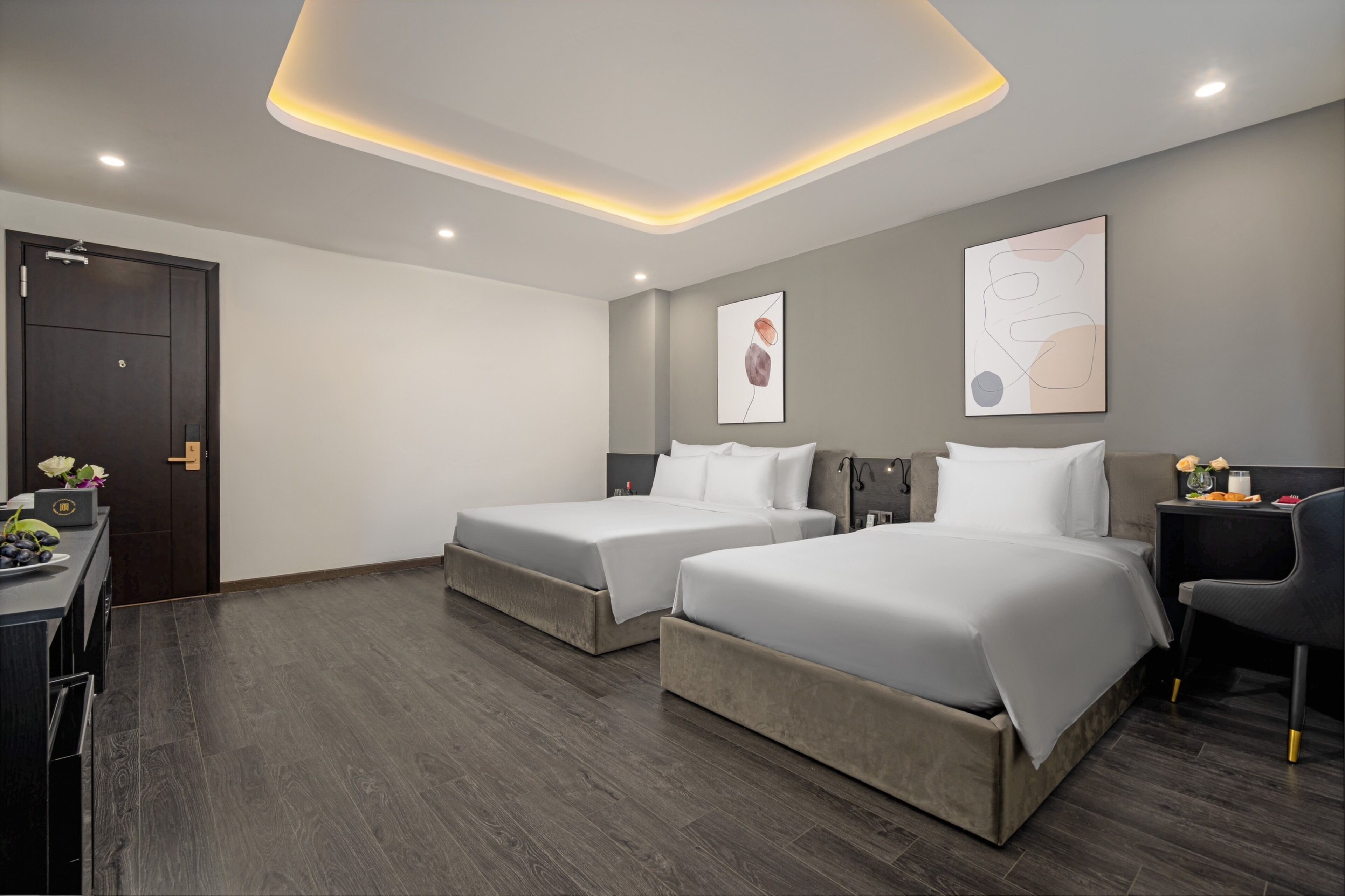 Quarto de hotel moderno com duas camas, uma escrivaninha e uma cadeira.