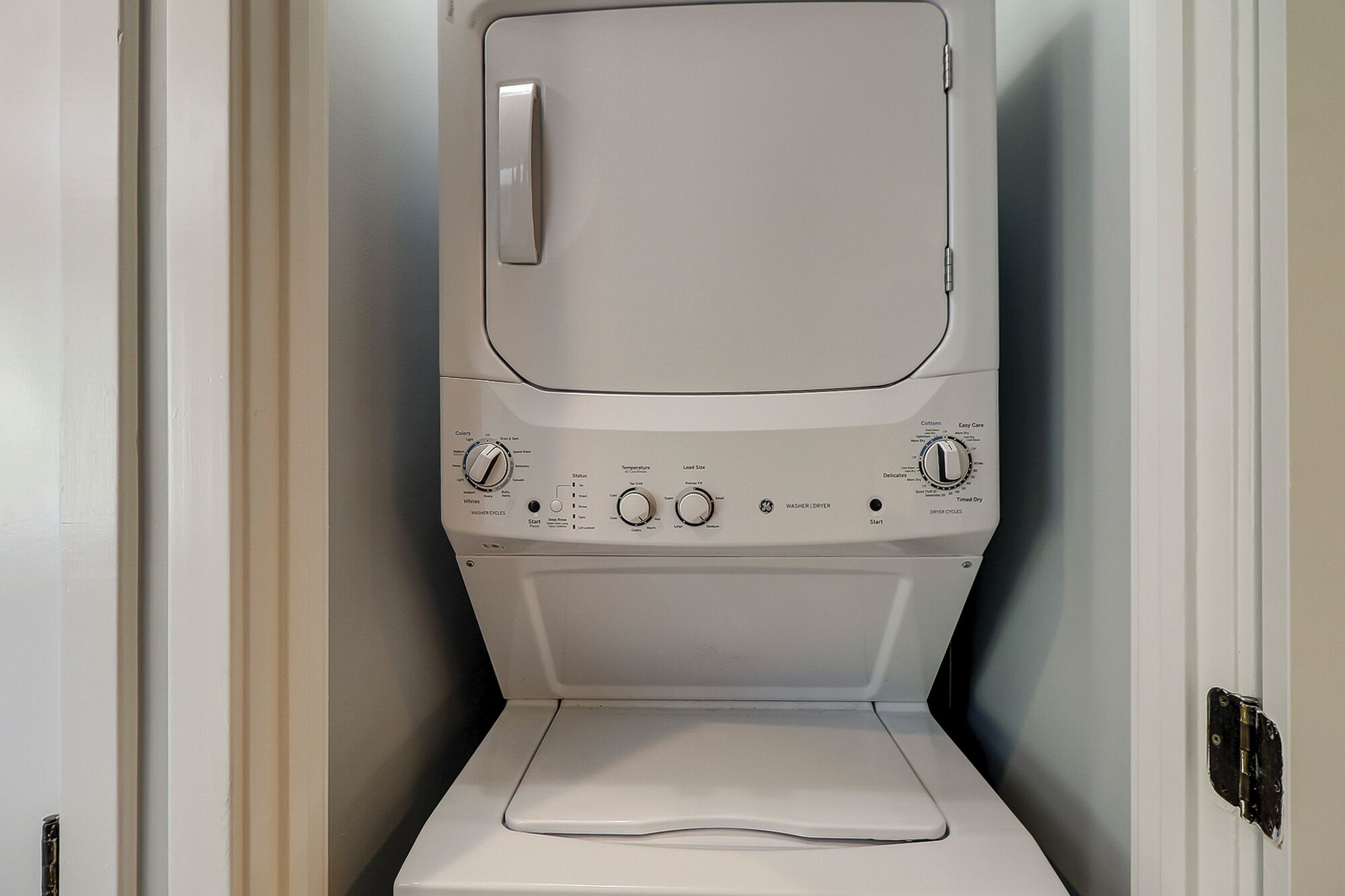 Eine weiße, wandmontierte Waschmaschine ist in einer Ecke des Raumes zu sehen.