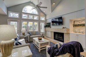 Relax in this spacious living room with a high ceiling, arched window, and fireplace.
