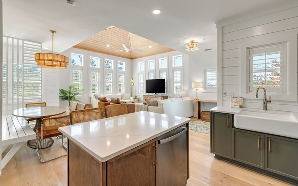 A modern kitchen with a central island, wooden cabinets, and a built-in dishwasher.