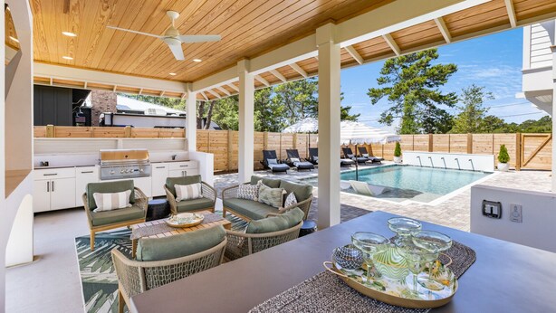 Un patio exterior con piscina, zona de estar y equipo para barbacoa.