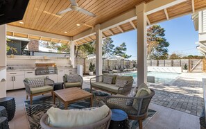 An outdoor patio with a grill, seating area, and a swimming pool.