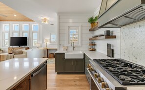 A modern kitchen with a central island, a built-in stove, and a large window.