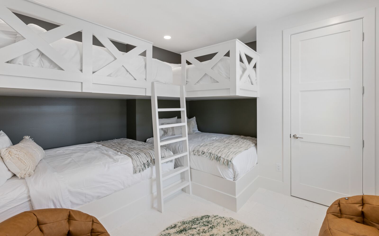 A bunk bed room with a ladder, a door, and two chairs.