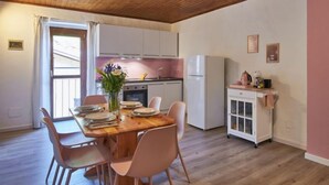 Eine moderne Küche mit weißen Schränken, einem Holztisch und rosa Stühlen.