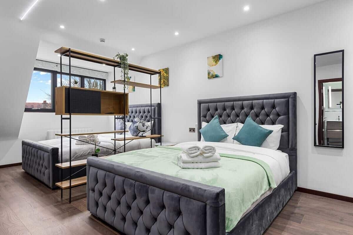 A modern bedroom with a large bed, a smaller sofa, and a built-in shelving unit.
