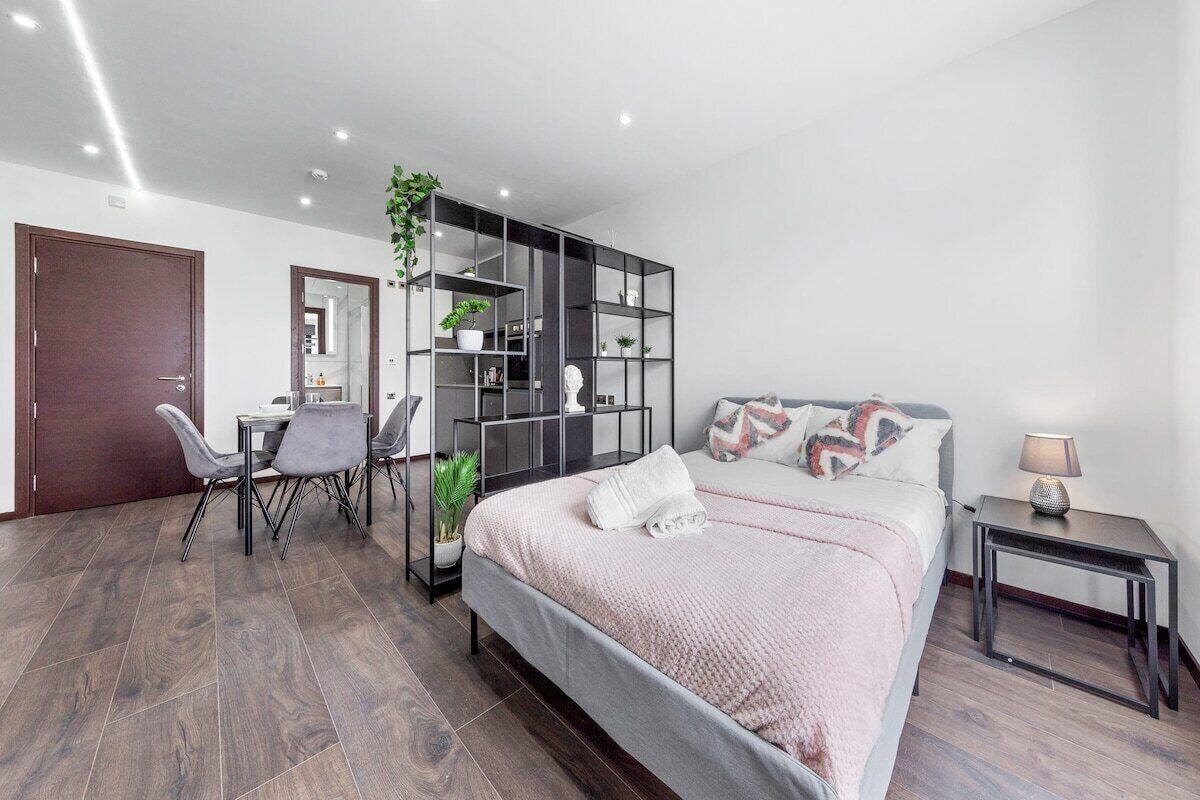A modern bedroom with a bed, bedside table, and a desk with chairs.