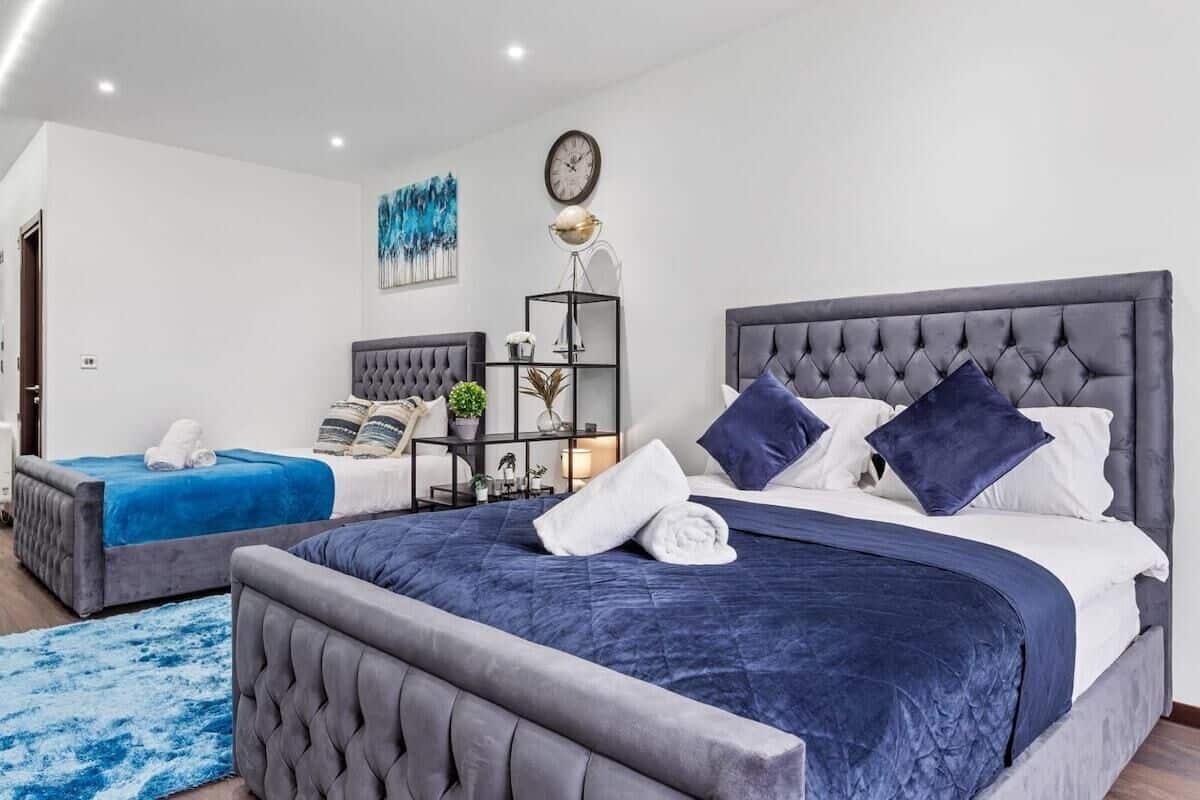 A modern hotel room with two beds, a large window, and a minimalist decor.